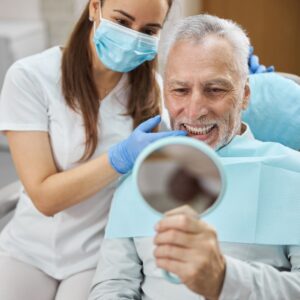 A dental patient looking at his smile in the mirror