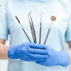 Gloved hands holding five dental tools
