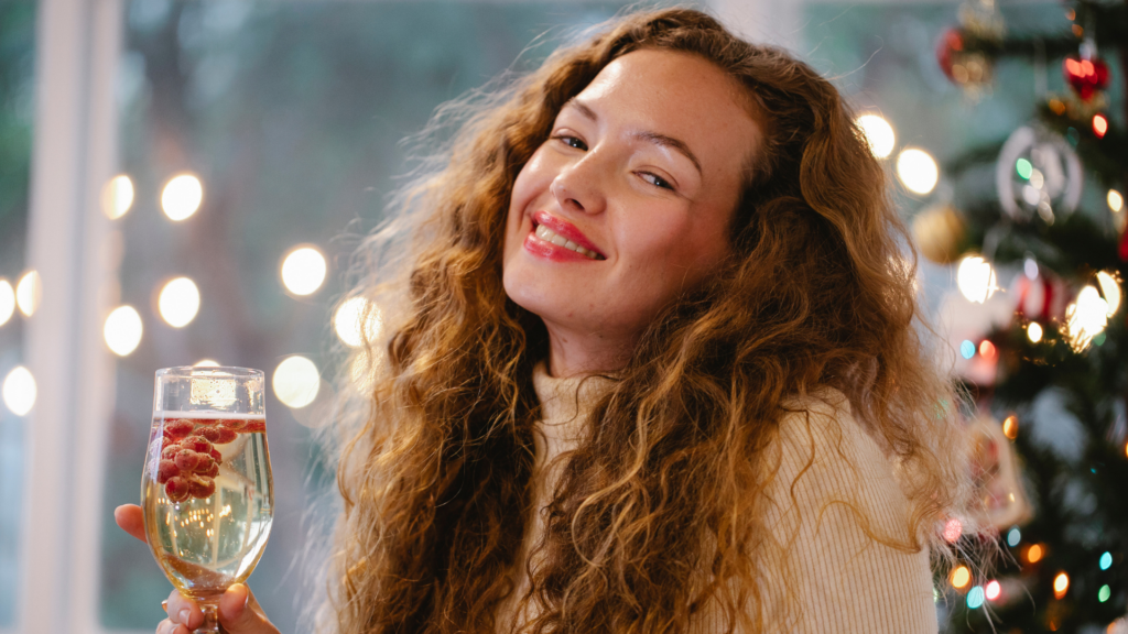 woman holding a holiday drink and smiling.